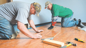 Installing hardwood flooring in Mario Ferri’s bedroom are CIA volunteers Mike Pressley (left), of Auburn Hills, and Oxford resident Jerry Jakuszeski, a parishioner at St. Joseph Catholic Church in Lake Orion. Photo by C.J. Carnacchio.