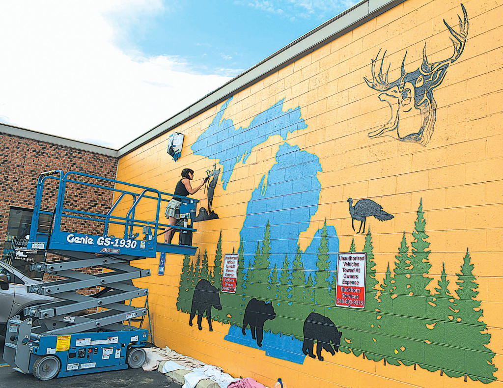 Lake Orion artist Kristi Blattel paints a mural on the front of 40 N. Washington St. in downtown Oxford. The theme fits right in with the new hunting specialty store, Beyond the Ears, that's preparing to open in the coming weeks. Photo by C.J. Carnacchio.