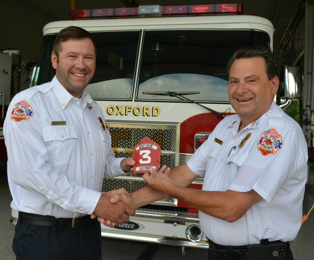 Fire Chief Pete Scholz (right) presents Stapp with his new leather helmet shield bearing the rank of captain. Photo by C.J. Carnacchio.