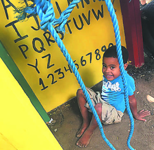 A Dominican boy enjoys the colorful new play structure that Hamilton and her fellow volunteers built at a K-5 school in Las Brazos.