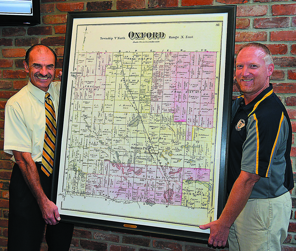 Oxford Township Clerk Curtis Wright (left) and Oxford Schools Superintendent Tim Throne hold a copy of an 1872 map of the township that shows it divided into nine small school districts. It will be on display in the board of education meeting room. A copy is already hanging in the township meeting room. Photo by C.J. Carnacchio.