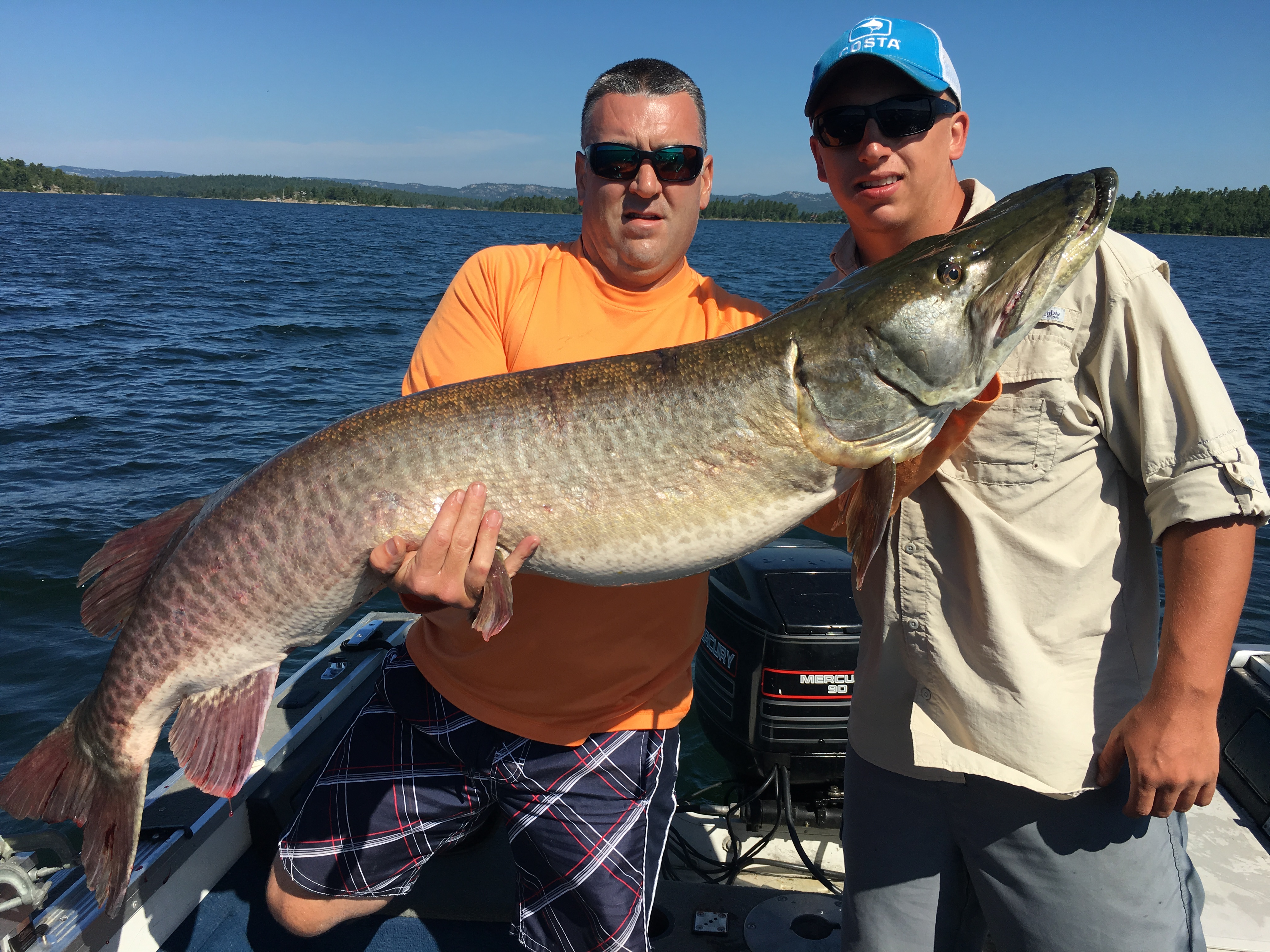 Orion Twp. residents Tim Berger (left) and Ethan Beckman pose with the 60-inch muskie they landed in Ontario, Canada's North Channel on July 26. Not pictured is Oxford resident Tom Berger, who was part of the team that landed this beast.