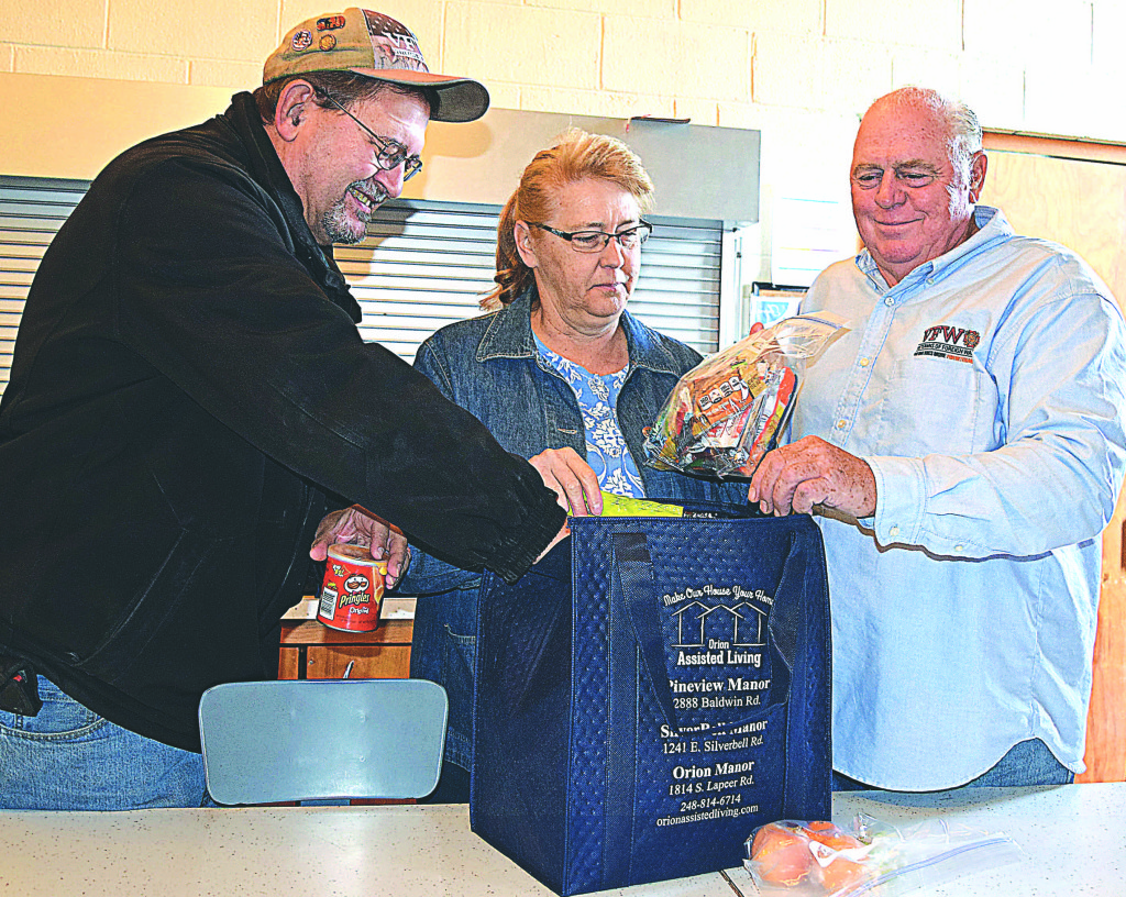 VFW Post 334 Quartermaster Chuck Haskin (left), VFW Auxiliary No. 334 President Kathy Hubbard (center) and VFW Post 334 Commander Jim Hubbard pack a Thanksgiving meal for someone in need. Photo by Elise Shire.