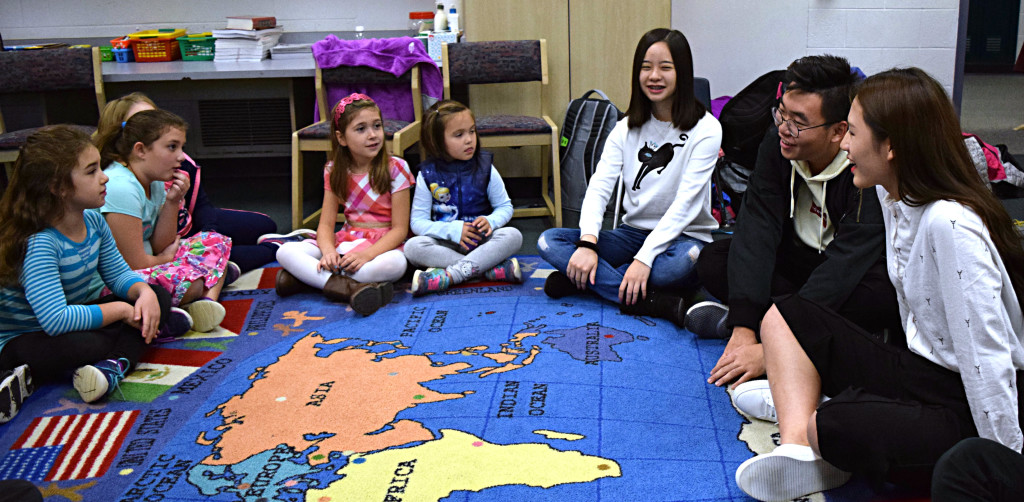 Daniel Axford second-graders (from left) Julianna DiGaetano, Madelynn Trajkovski, Emmeline Geisler, Adele Flynn listen as Oxford International students Lin Shi, Hao Yu, and Jiamin Zheng answer questions about Chinese culture. Photo by Elise Shire.