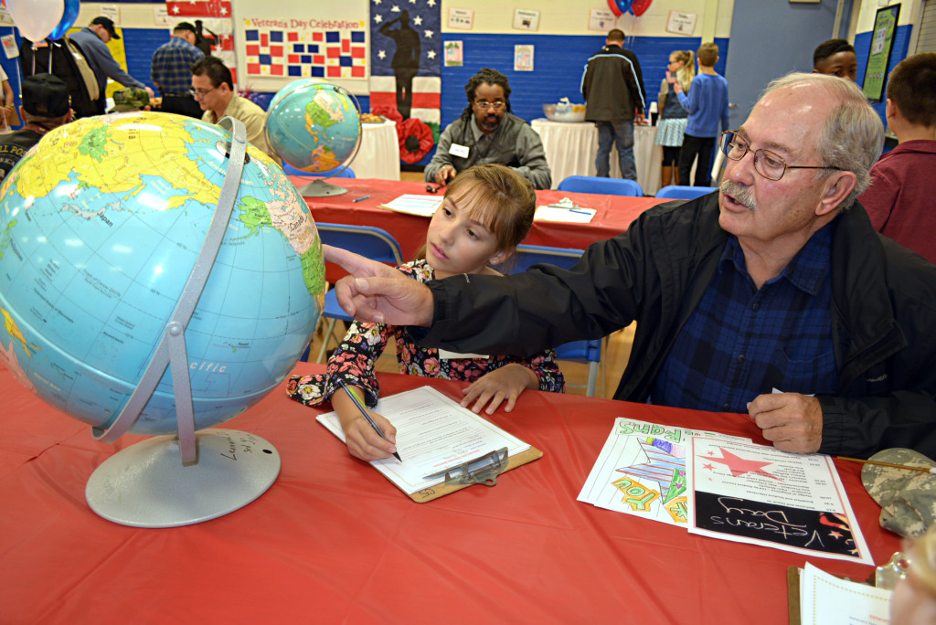 Almont resident Gary Kenney, a U.S. Navy veteran who served from 1960-67, uses a globe to show his granddaughter Paige Cherry, a fifth-grader, the places he visited on the Uncle Sam plan. Photo by C.J. Carnacchio.