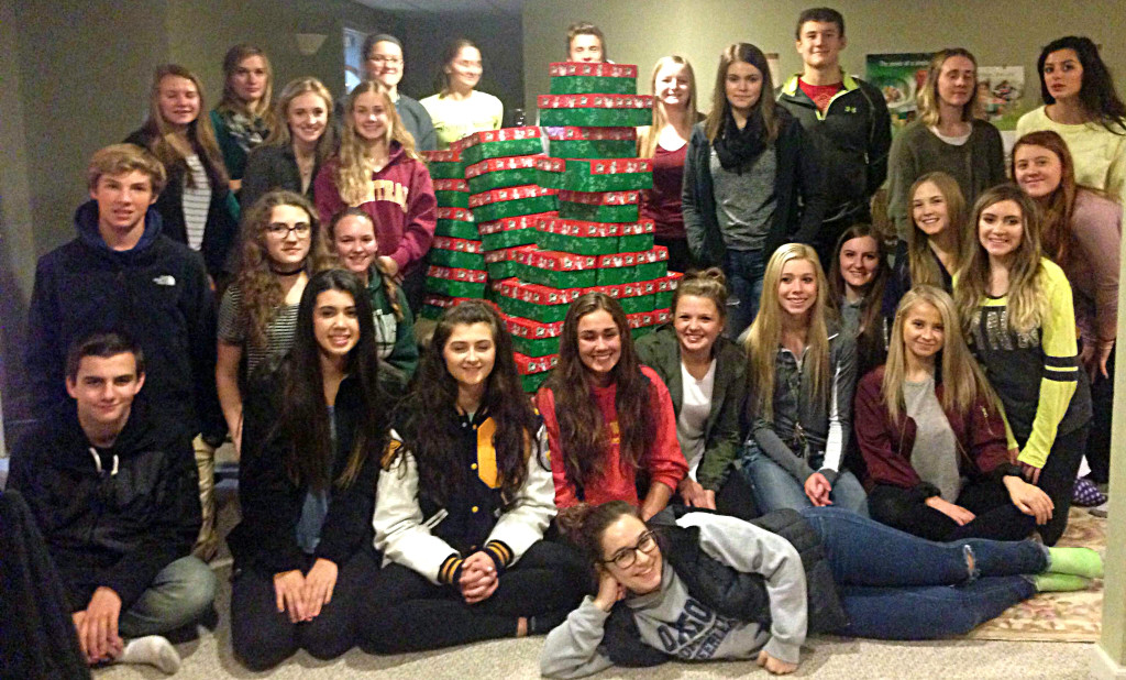 Oxford High School's chapter of the National Honor Society poses with the stack of boxes they filled with hygiene products, school supplies, and toys for children in need.
