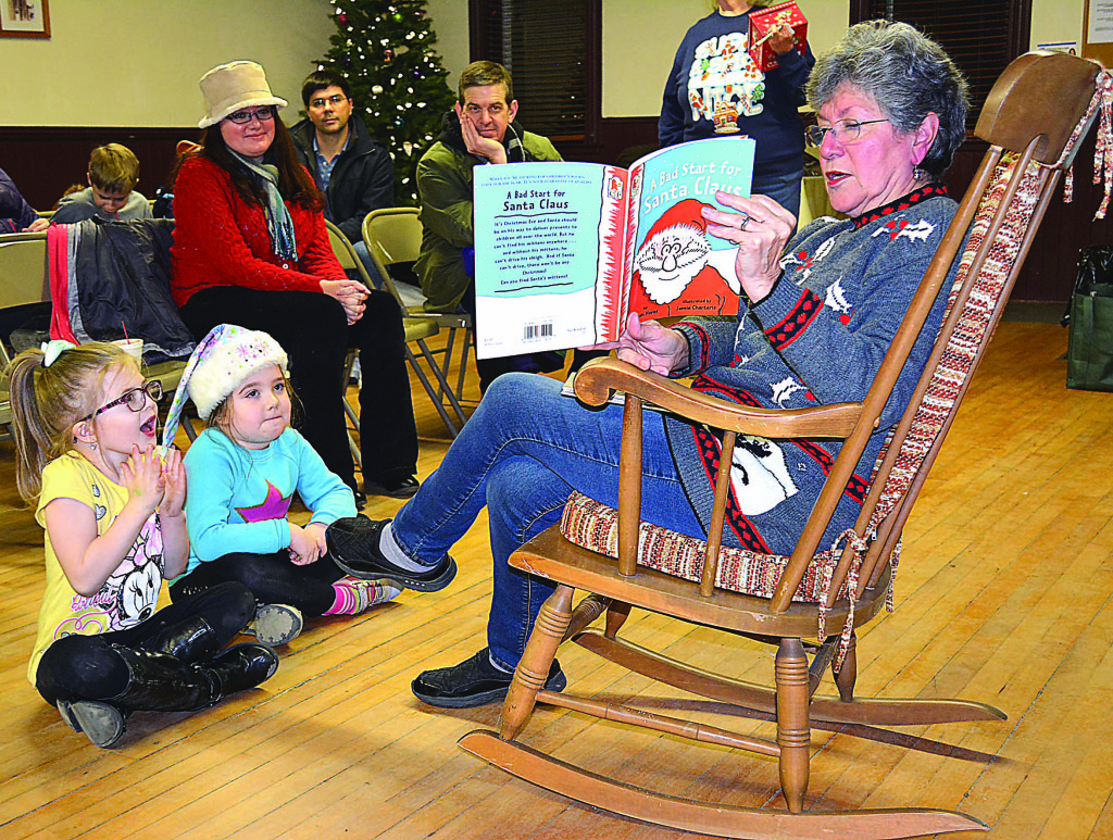 Longtime Leonard Village Councilwoman Char Sutherby reads the story “A Bad Start for Santa Claus.” Listening are Ella Munro (left) and Leonard kindergartner Dory Enyart. Seated behind them are Donovan and Amber Enyart, of Oxford.