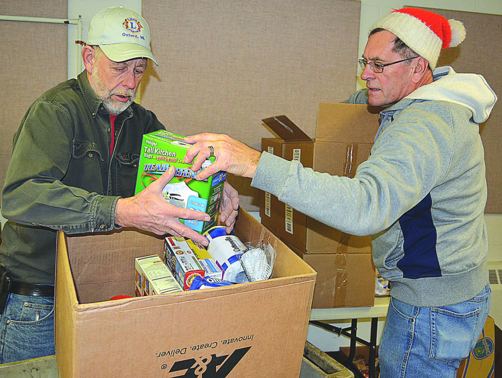Oxford Lions Club President Ron Wood (right) and Lions Member Art Miller pack a box with food and household items for folks in need. Photo by C.J. Carnacchio.