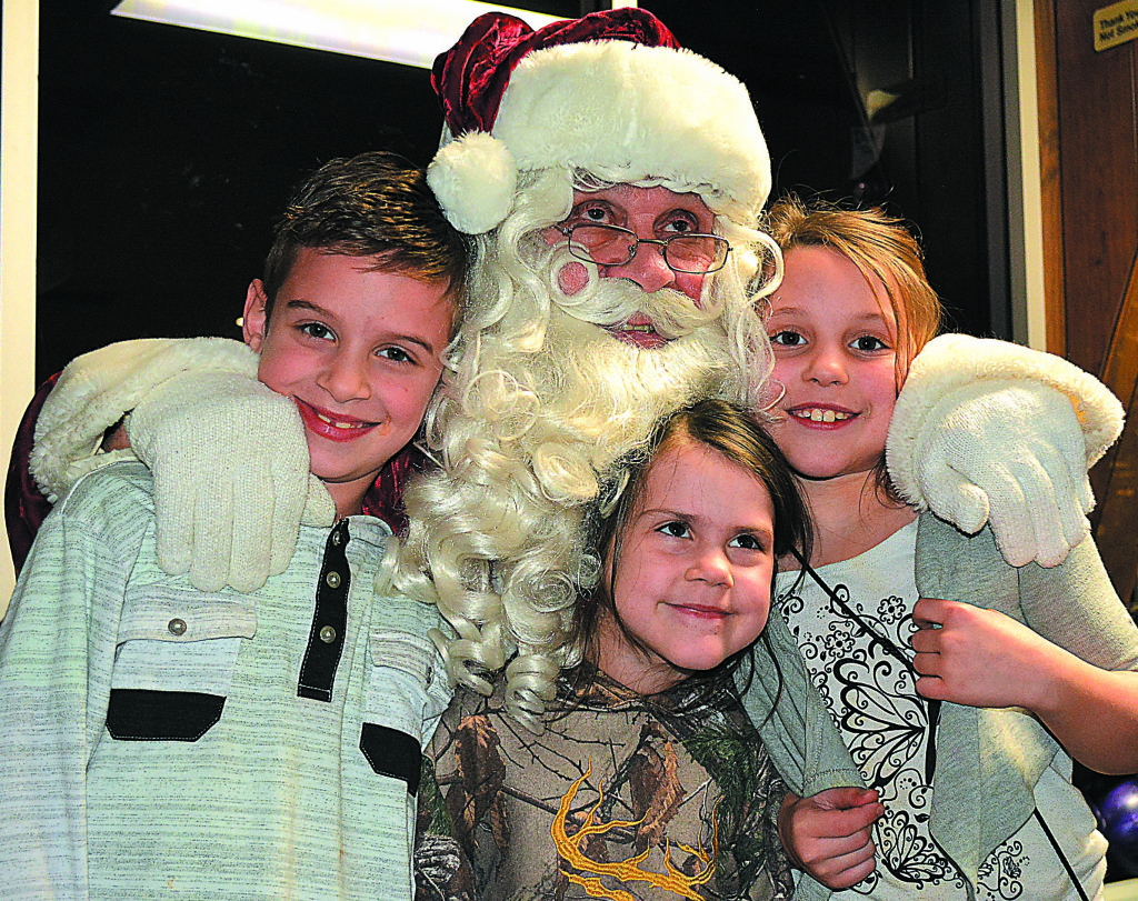 Posing for a photo with Santa Claus are (from left) Oxford residents Jay Ostrowski, Madalyn Ramaekers and Halie Ramaekers. Photo by C.J. Carnacchio.