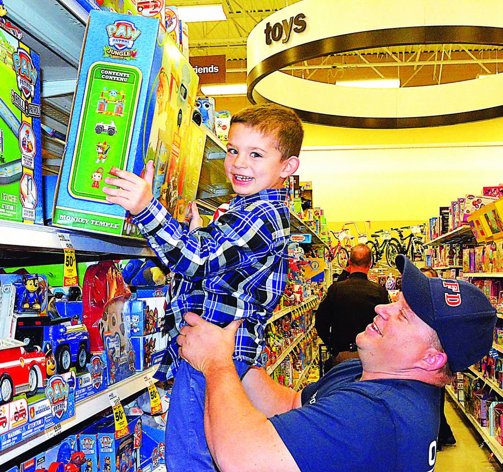 Oxford firefighter Darin Balinski helps Neo Parraghi reach a toy on the top shelf. Photo by C.J. Carnacchio.