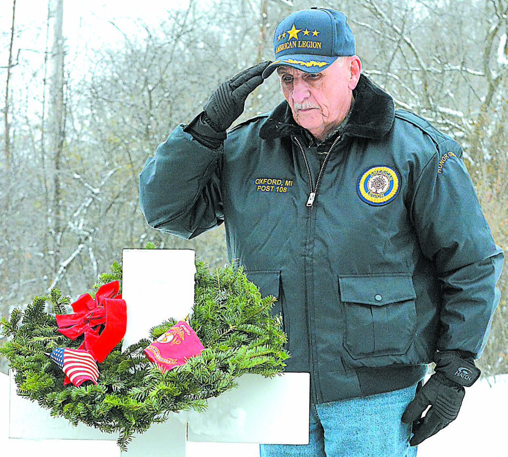 Mike Ledford, a veteran of the Marine Corps and trustee for Post 108, salutes after placing a wreath on a cross representing a branch of the U.S. Armed Forces.