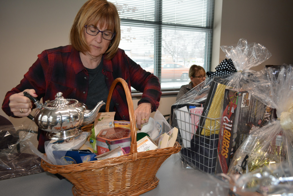 Lyn Klages, secretary of the Oxford Public Library Friends, packs a tea-themed basket for the silent auction fund-raiser.