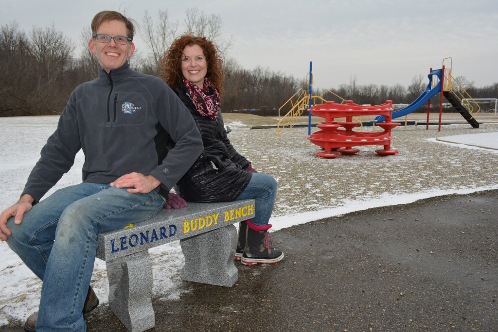 Richard and Carrie Muir, owner of Romeo Monument Station, sit on the new Buddy Bench installed Friday on the playground at Leonard Elementary School. Photo by C.J. Carnacchio.
