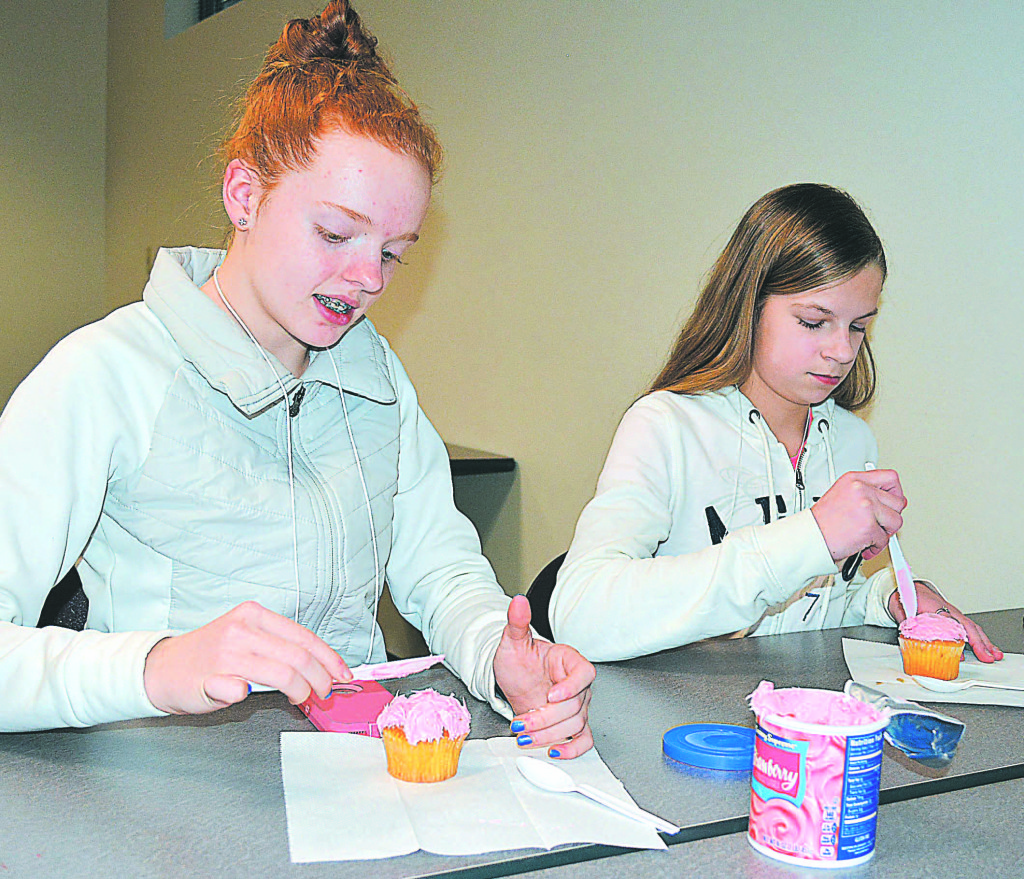 Oxford Middle School seventh-graders Marissa Haywood (left) and Ashley Bales decorate their cupcakes with pink frosting.