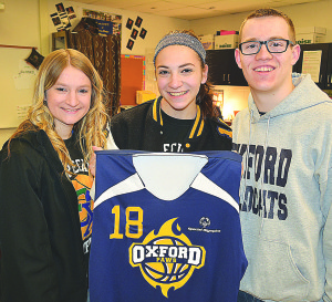 OHS seniors Gracie Freiberg (from left), Katie Romano and Jonah Grove pose with one of the new Oxford PAWS jerseys. It was their idea to get new uniforms for the team and the Oxford Wildcat Booster Club paid for them.