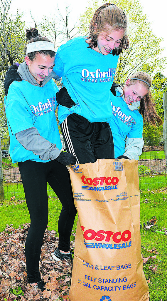 OHS students Alyssa Kessler (left) and Leah Freiberg (right) use Gina Guy to pack down the leaves in a lawn bag.