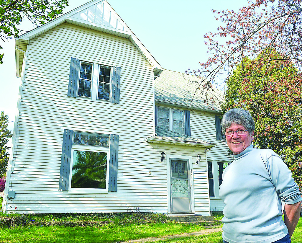 Leonard Village Councilwoman Char Sutherby poses outside 309 E. Elmwood St., built in 1870. It’s one of the two oldest homes in town. She is looking for folks to join her on the new Leonard historic committee and help research 45 homes that are at least 100 years old. Photo by C.J. Carnacchio.