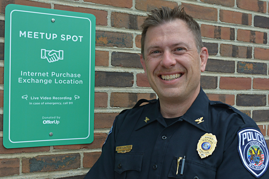 Acting Oxford Village Police Chief Mike Solwold stands next to the sign behind the W. Burdick St. municipal complex that lets people know it’s a safe place to conduct their internet exchanges. Photo by C.J. Carnacchio.