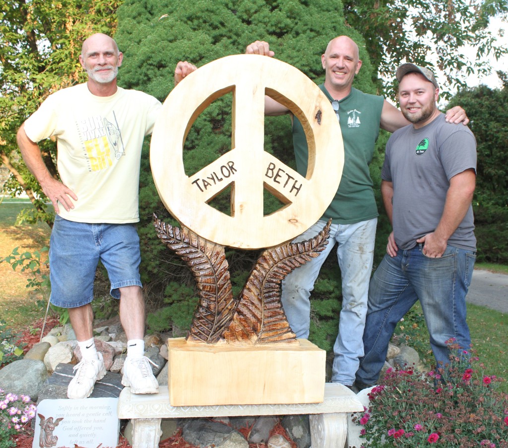Chris Woityra (from left), chainsaw carver Gary Elzerman and Chad Cartwright, owner of the Oxford-based Mr. Tree. Photo by C.J. Carnacchio.