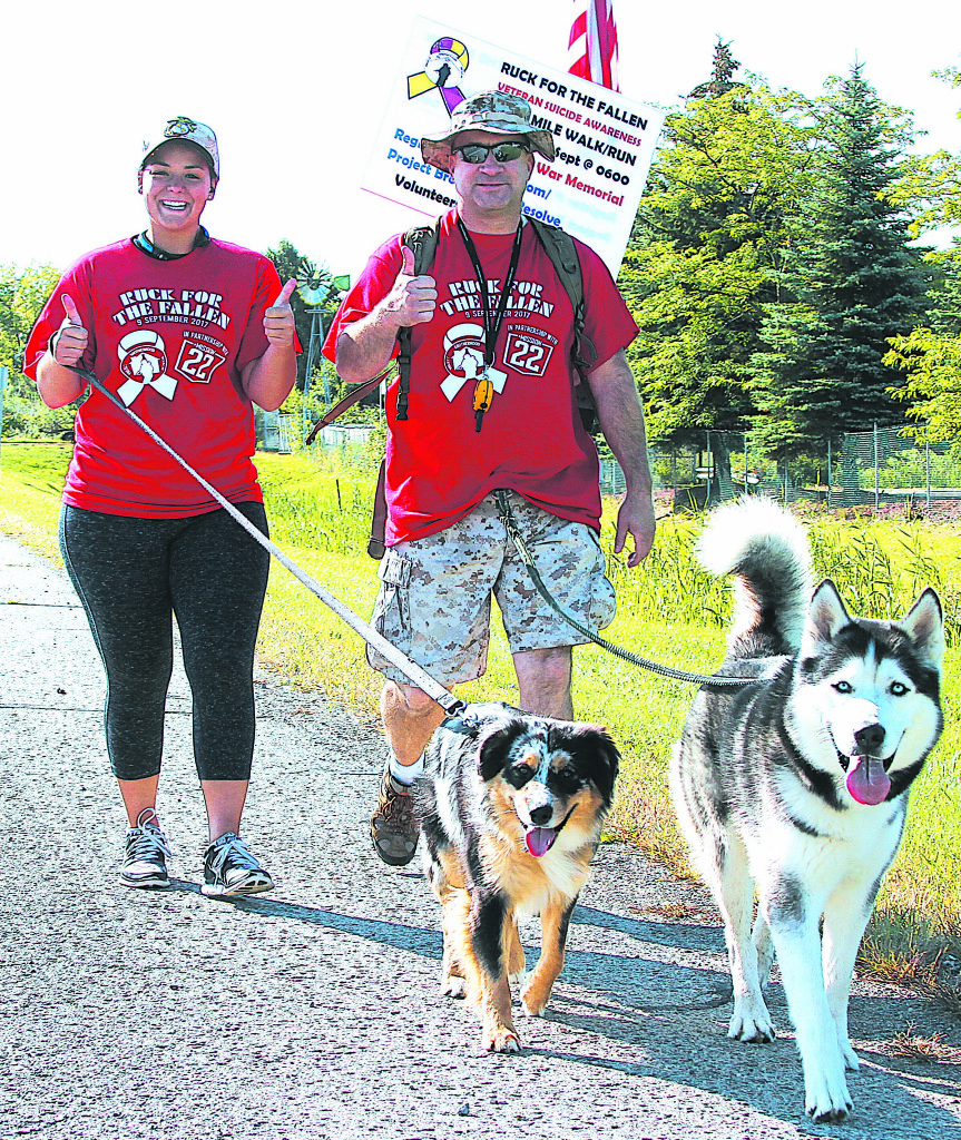 Lapeer residents Gary Morrell (right) and Kayla Morrell walk with their dogs Meeko (left) and Striker.