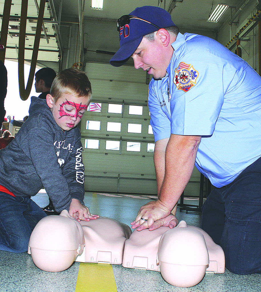 Oxford firefighter Anthony Bono (right) shows Colton Wallace, 5, of Oxford, how to properly do chest compressions.