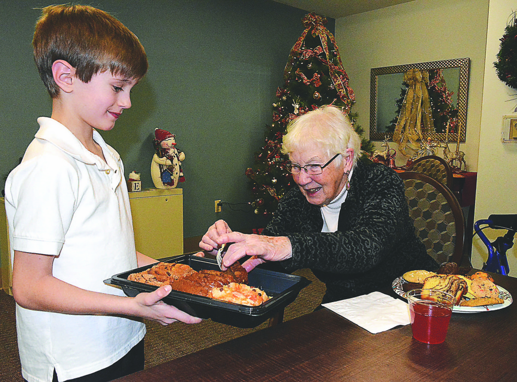 Clear Lake student Grant Saulter serves sweet holiday treats to Hope Senior resident Elizabeth Hartjen. Photo by C.J. Carnacchio.