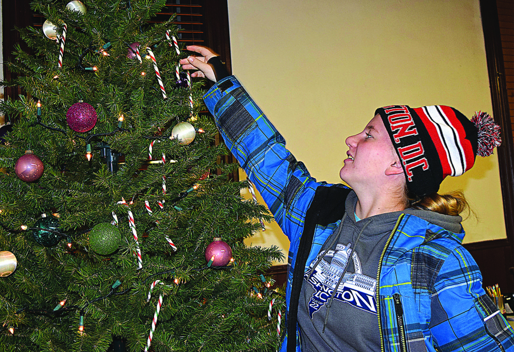 Ashley Persico, 14, puts a candy cane on the Christmas tree inside historic Rowland Hall.