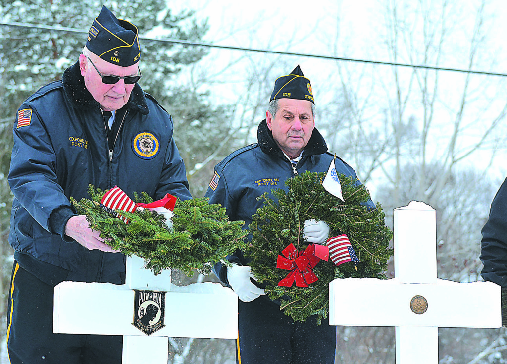 James Montgomery (left) places a wreath on a cross representing service members whose last known status was either prisoner of war or missing in action. Watching him is Vietnam veteran Juan Vazquez.