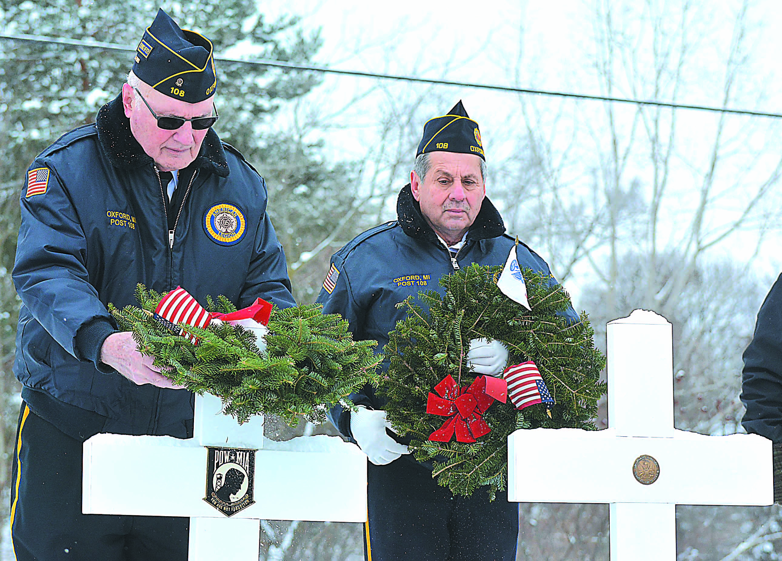 James Montgomery (left) places a wreath on a cross representing service members whose last known status was either prisoner of war or missing in action. Watching him is Vietnam veteran Juan Vazquez.