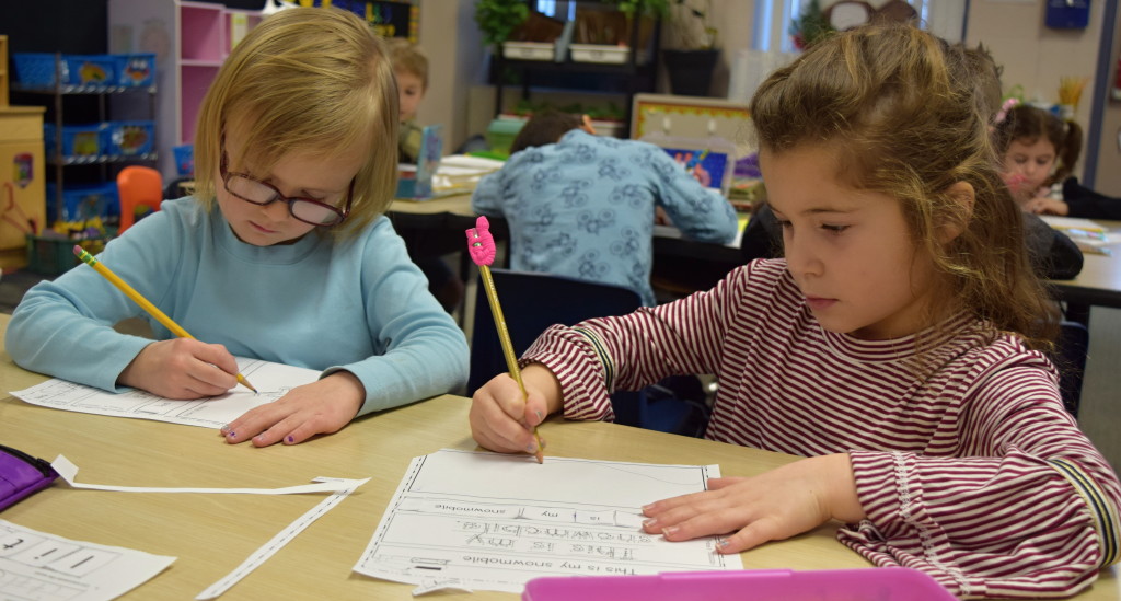 Dayana DeFauw (left) and Bella Capogna, kindergartners at Daniel Axford Elementary, practice their handwriting. Photo by Elise Shire.