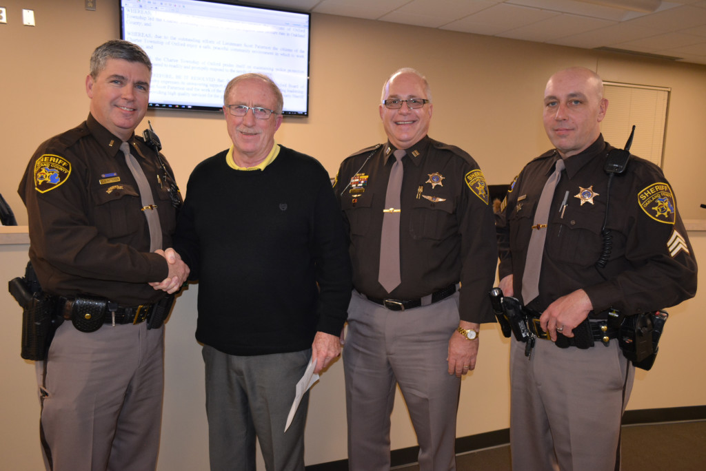 Oakland County Sheriff’s Lt. Scott Patterson (far left) shakes hands with Oxford Township Supervisor Bill Dunn following the board passing a resolution honoring him. With them are Sheriff’s Capt. Dale Miller (left) and Sgt. Frank Lenz. Photo by C.J. Carnacchio.