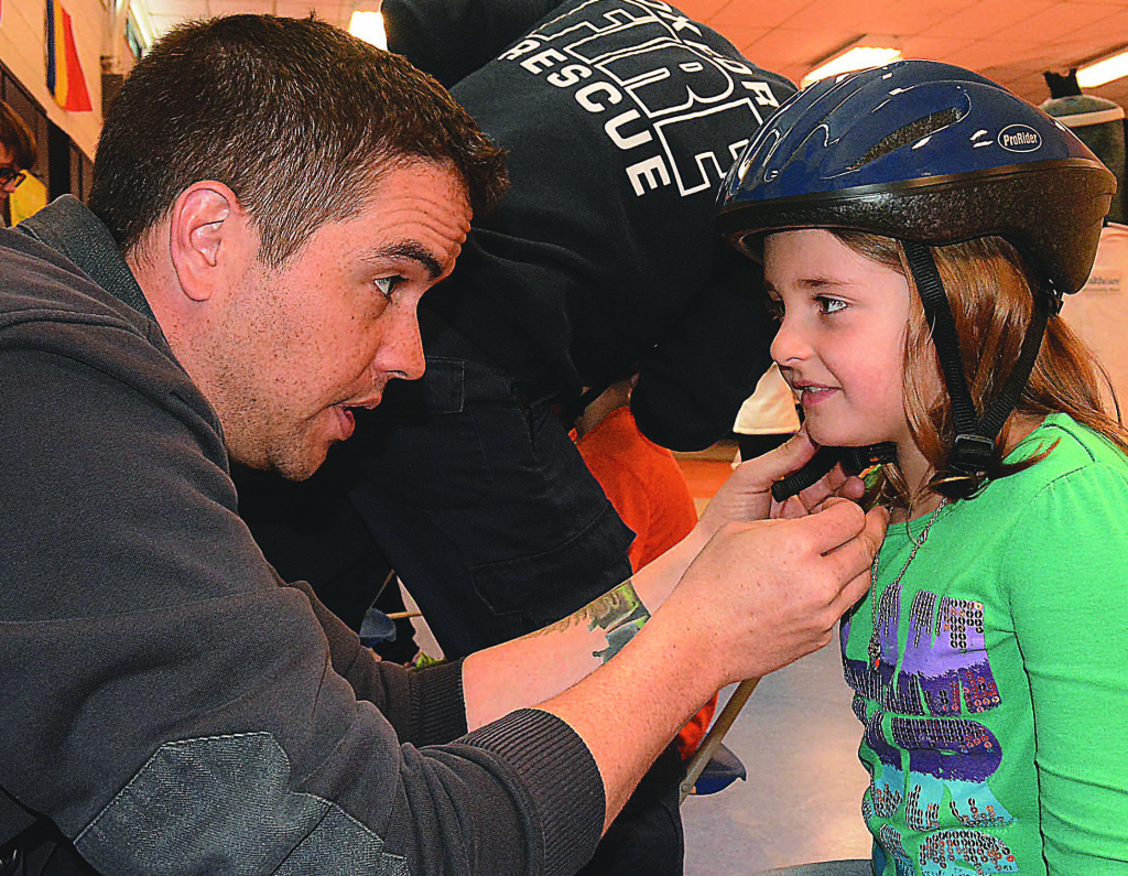 Clear Lake Elementary second-grader Tori Egbert gets fitted for a new bicycle helmet with the help of Oxford firefighter Justin Templeton. Photos by C.J. Carnacchio.