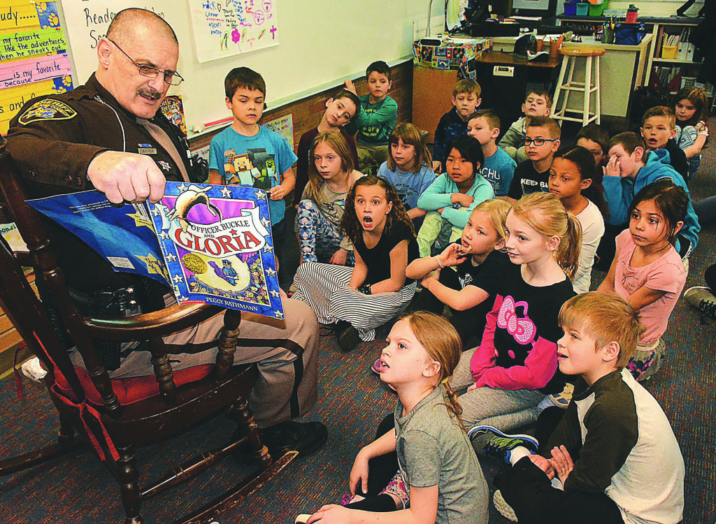 Oakland County Sheriff’s Reserve Deputy Bruce Mack reads “Officer Buckle and Gloria” to Clear Lake second-graders in teacher Jennifer Clemens’ classroom. Photo by C.J. Carnacchio.