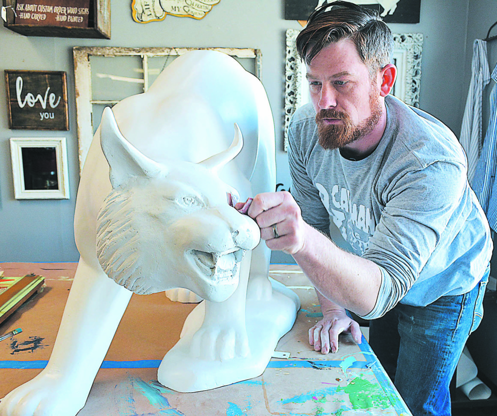 Craig Shagena, owner of Caveman & Pip in downtown Oxford, sands his Wildcat statue in preparation to paint it for Experience Oxford April 20-22. Photo by C.J. Carnacchio.