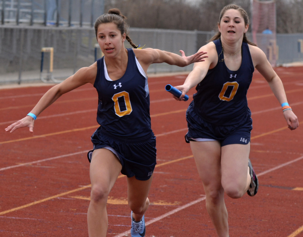 Emma Vanloon (left) reaches for the baton being handed off by Micah Dymond. Photo by C.J. Carnacchio.