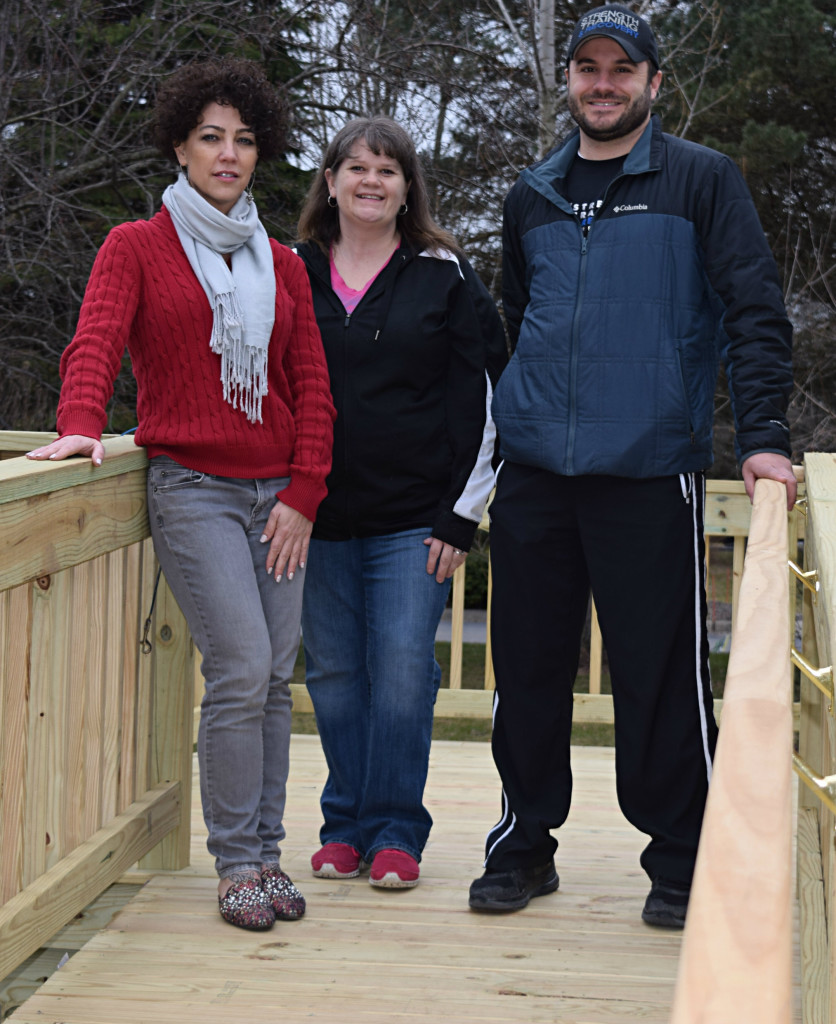 Marcie Gruenberg (center) stands on the deck of a wheelchair ramp built outside her family’s Oxford home with the help of Guiding Star Foundation President Sophia Bong (left) and Vice President Joe Bongiovanni. Photo by Elise Shire.