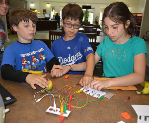 Oxford siblings (from left) Josh, Michael and Rebecca Secord have fun testing out the new Makey Makey invention kit available at the Oxford Public Library. Photo by C.J. Carnacchio.