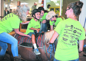 Banbury Cross rider Alex Williams (center) is a happy little guy. Helping him mount Story the horse are Banbury instructors Jessica Leroux and Jessica Moore along with volunteers Michelle Schneider and Christianna Sauve. Photo by C.J. Carnacchio.