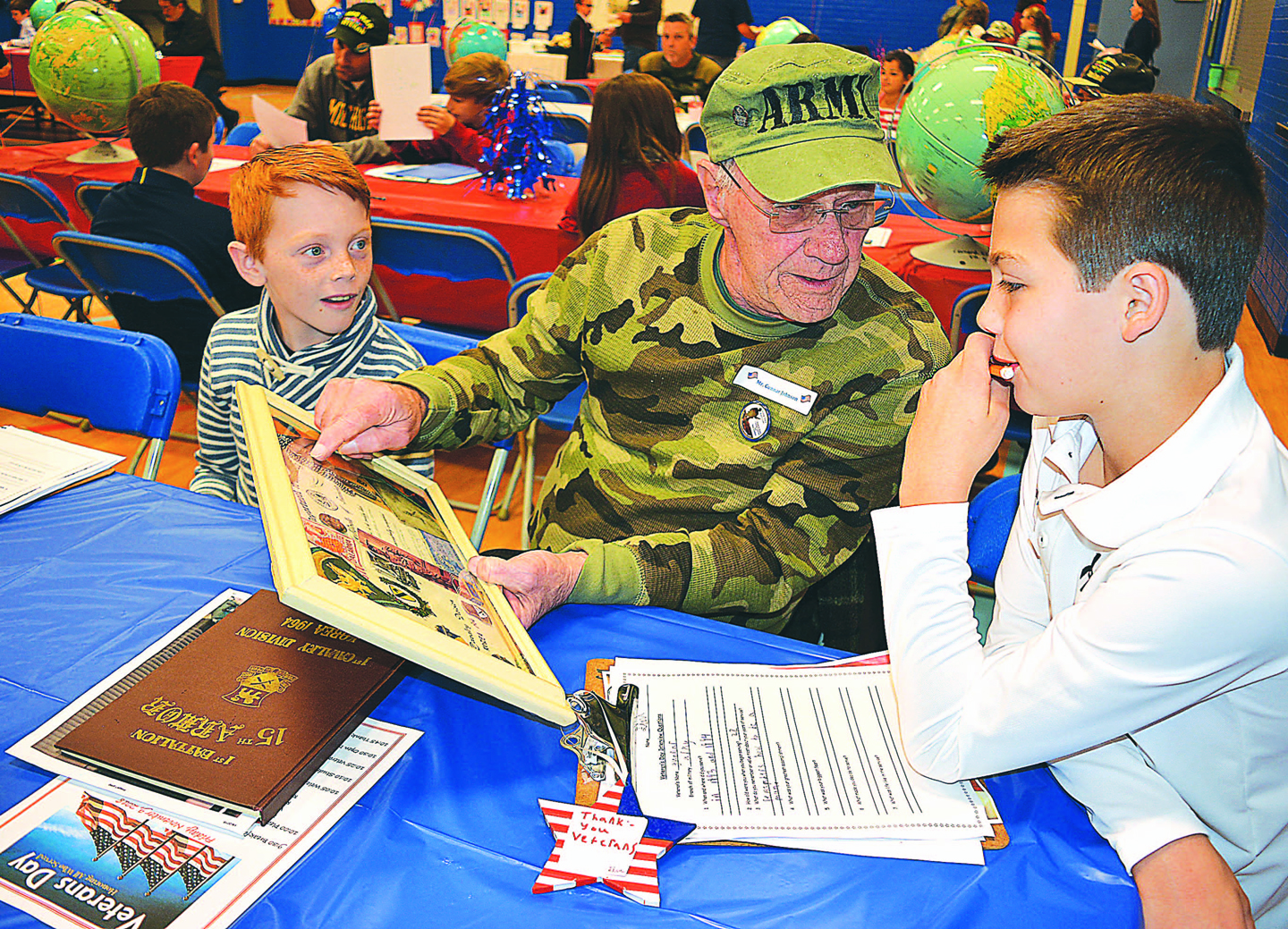 Gunnar Johnson (center), a U.S. Army veteran who served from 1963-64, shares his military experiences with fifth-graders Gavin Lewis (left) and Finn McDevitt. Photo by C.J. Carnacchio.