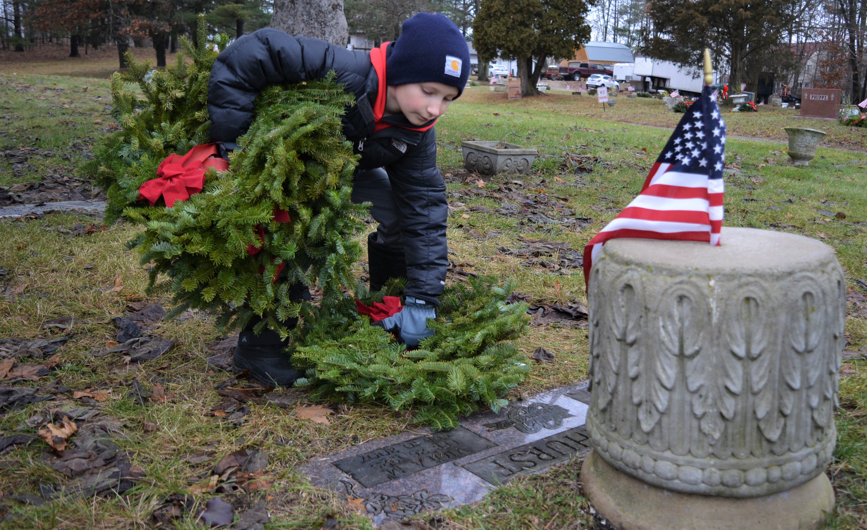 Cub Scout Christian LaBelle, a member of Oxford Pack 4, places wreaths on the graves of veterans buried in Ridgelawn Memorial Cemetery. Photo by C.J. Carnacchio. 