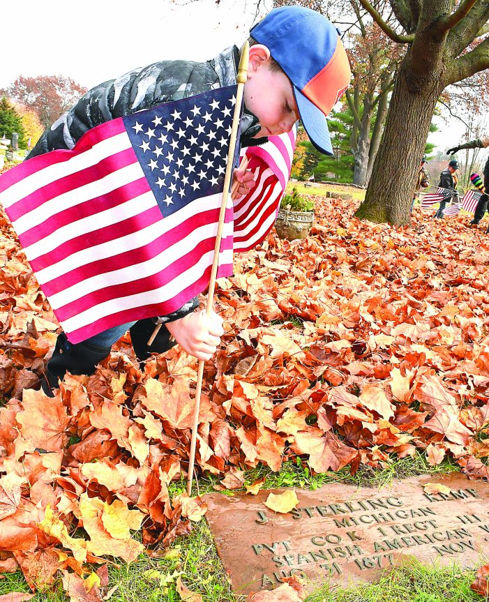 Local scouts salute deceased  veterans, place flags on graves